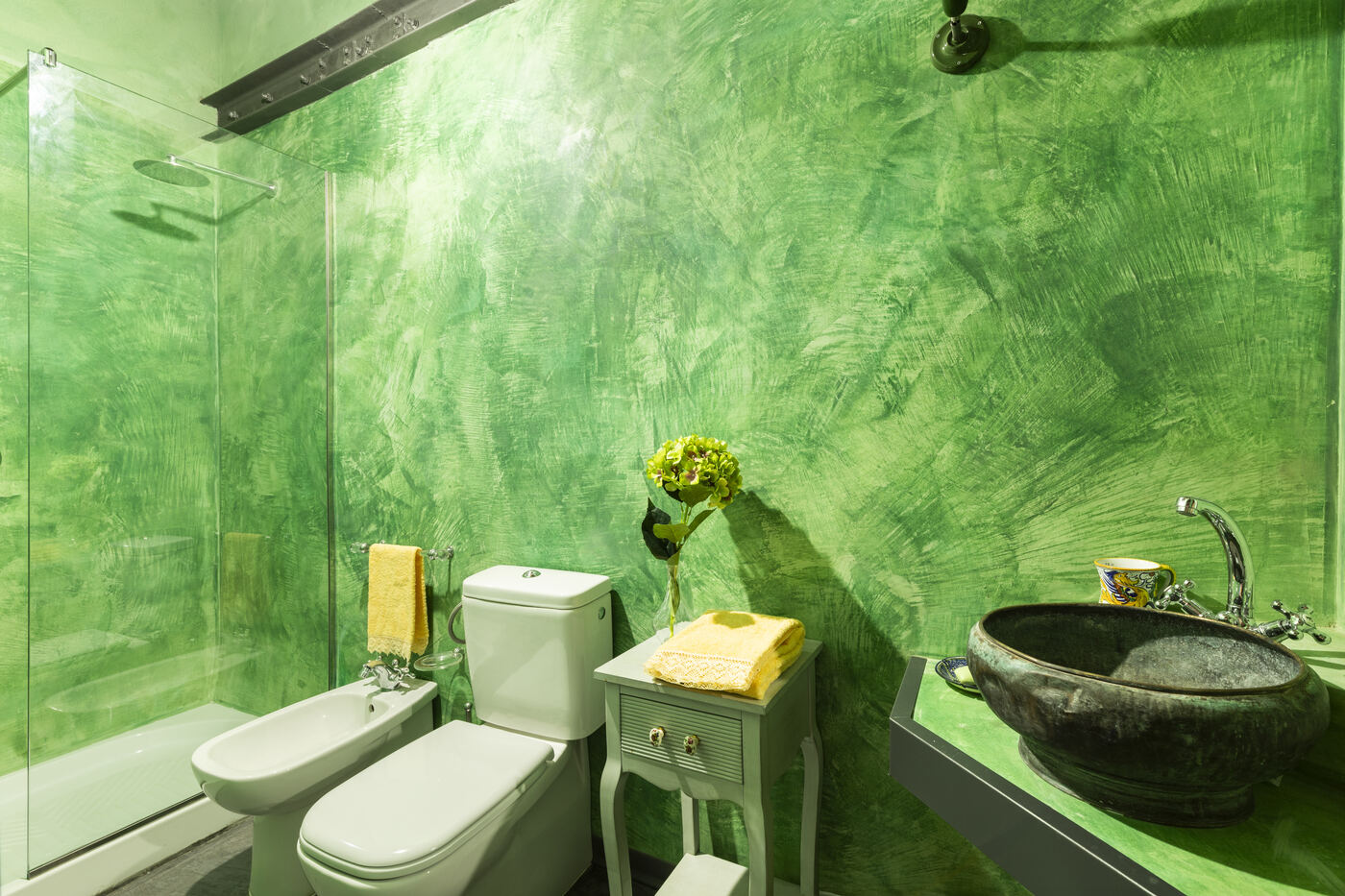 Bagno verde con box doccia e lavabo in pietra