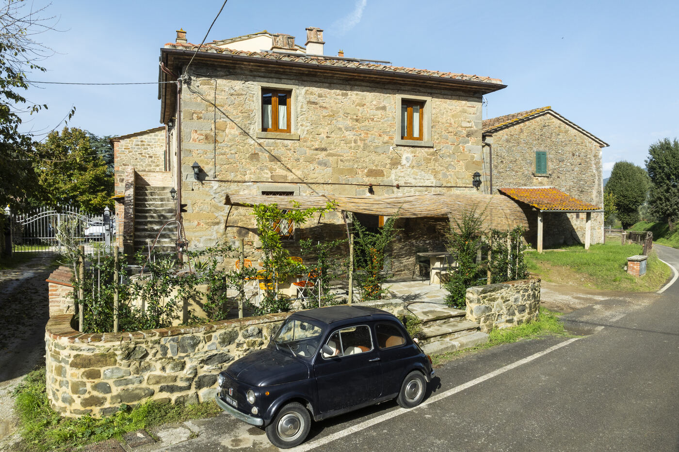 Facciata del casale con Fiat 500 e cipressi